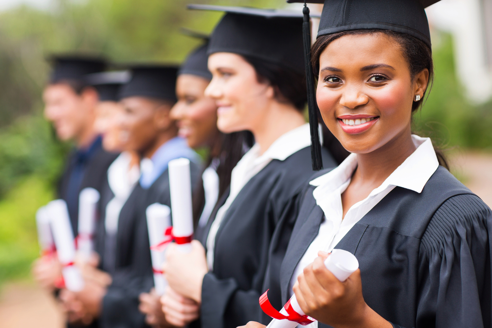 Young woman receives diploma next to other graduates